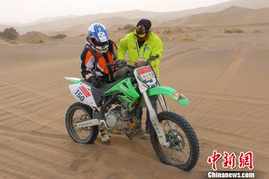 圖為10月19日，拉力賽裁判帶著救援車返回比賽途中，給故障摩托車加油。　耿丹丹 攝